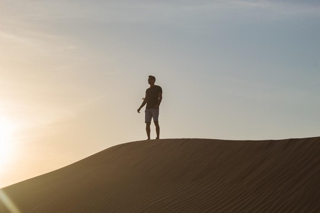 a man standing on top of a sand dune