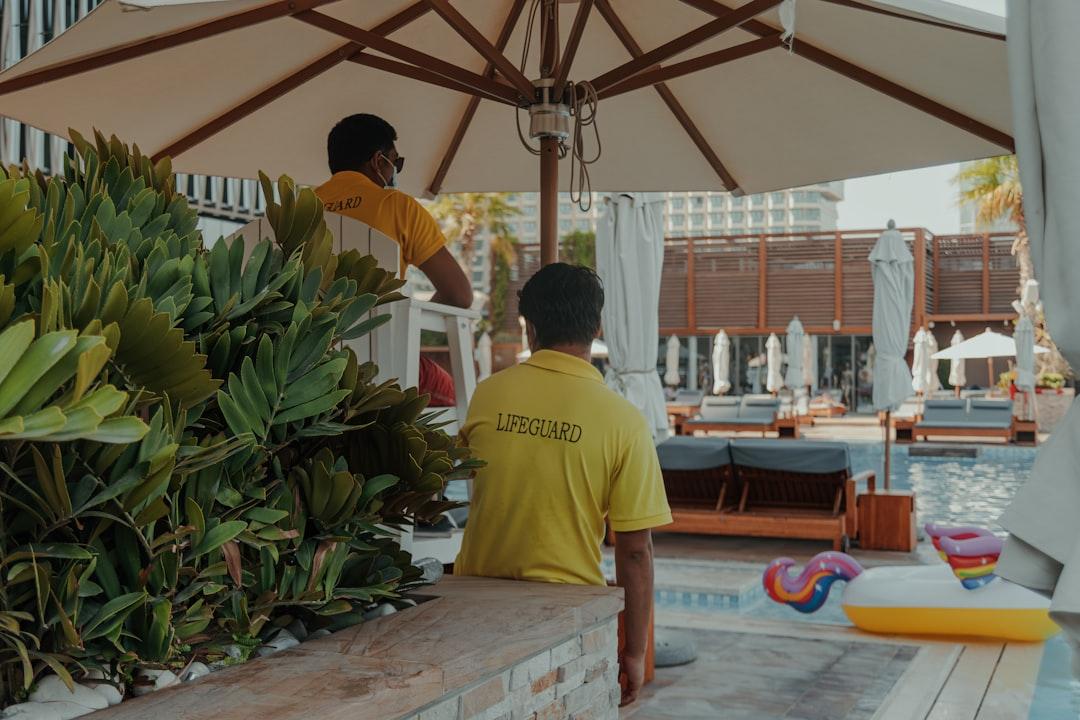 A man standing under an umbrella next to a pool
