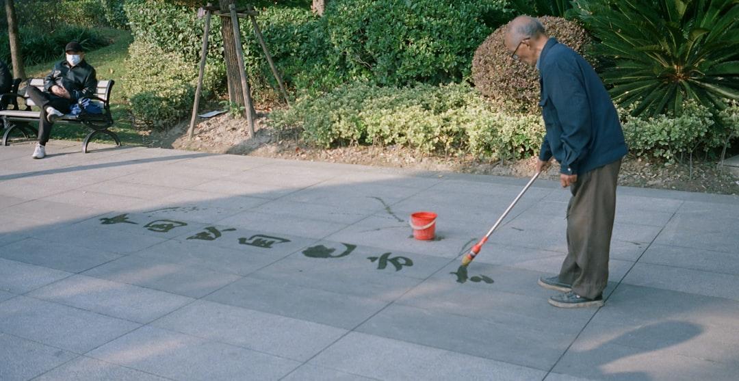 a man standing on a sidewalk with a bucket and a mop