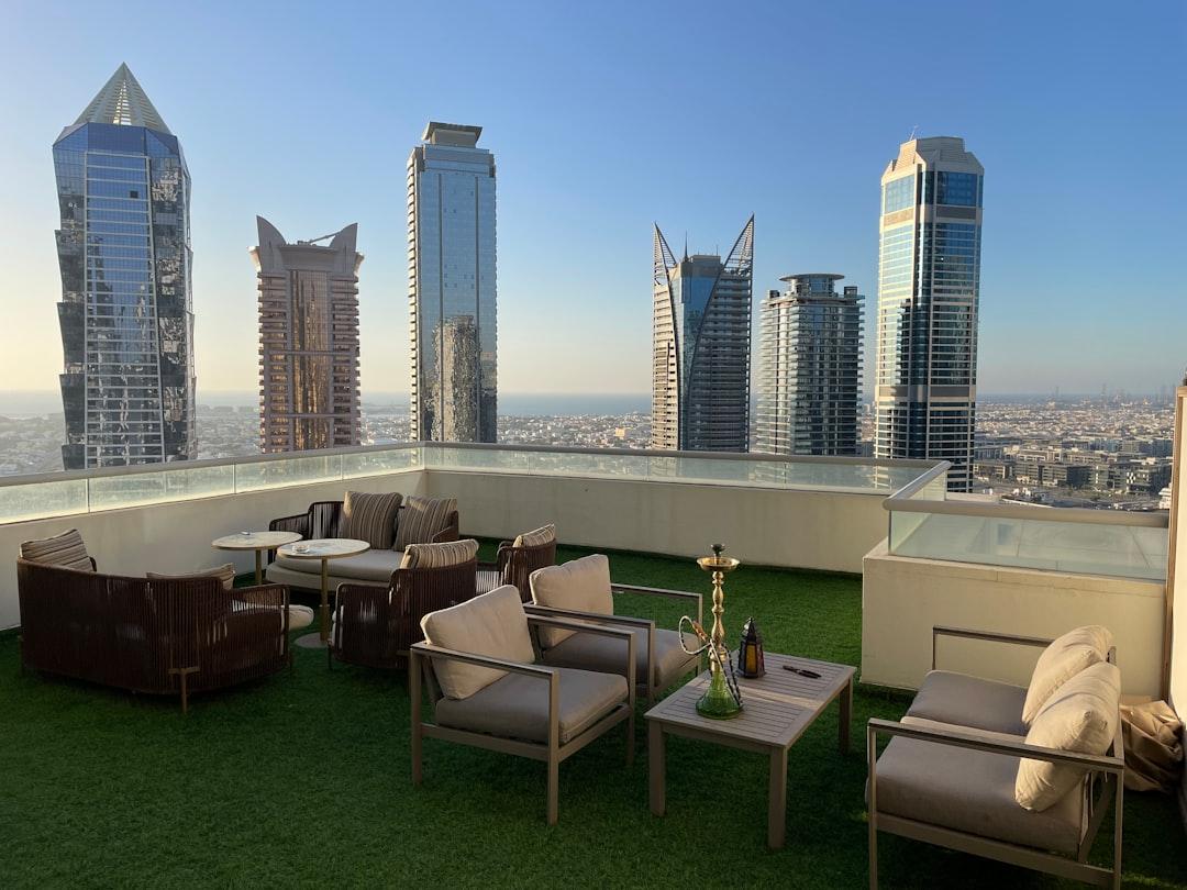 a balcony with chairs, tables, and a view of the city