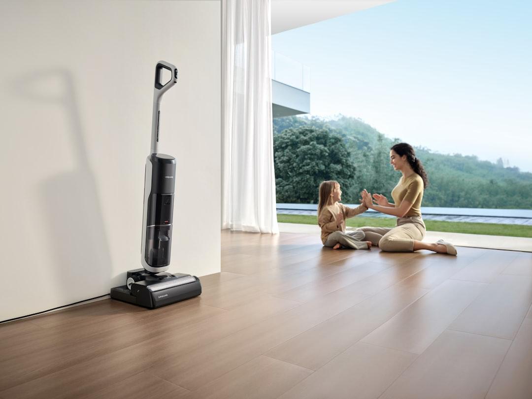 Woman and child playing near vacuum cleaner.